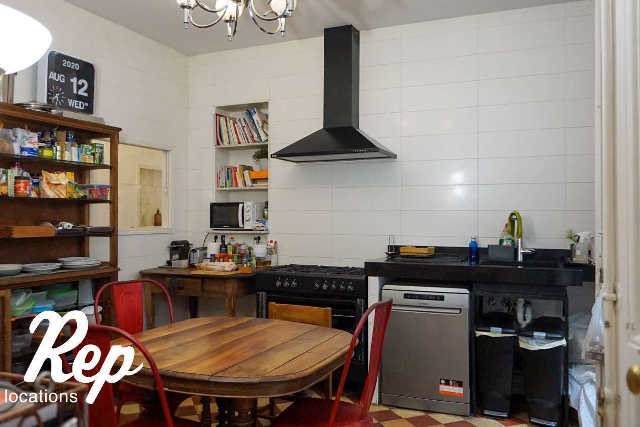 Black kitchen with white walls and a wooden table
